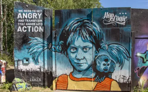 En färgstark graffiti i Stockholm med en flicka och en apa. Texten "WE NEED TO GET ANGRY AND TRANSFORM THAT ANGER INTO ACTION" syns tydligt.