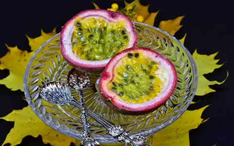 Två halvor av passionsfrukt på en kristallskål, omgivna av höstlöv. Dessa exotiska frukter ser läckra ut!