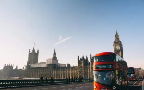 En röd dubbeldäckare passerar Big Ben och Houses of Parliament. En perfekt dag för en **turista i London**.