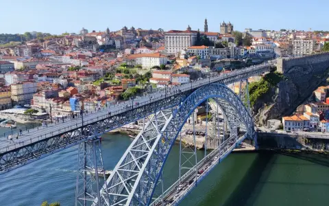 Imponerande bro över Dourofloden i norra Portugal, med en stad full av färgglada hus och kyrkor i bakgrunden.