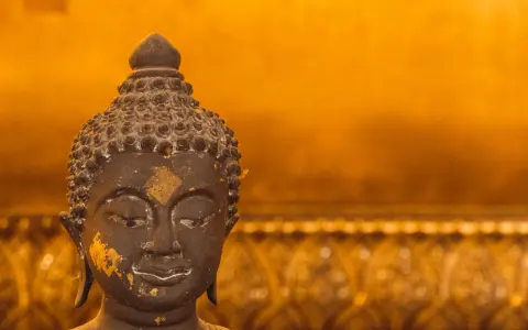 Buddhas ansikte med guldfolierester, en påminnelse om lugn under regnperioden i Asien.