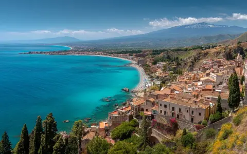 Vacker kustvy med turkost hav, en strand och en stad vid foten av Etna. Perfekt för din sicilien reseguide.