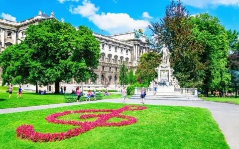 En vacker sommardag i Wien. En blomsterformation i form av en fiolnyckel lyser upp gräsmattan framför Mozarts staty. Ett perfekt ställe att se i Wien.