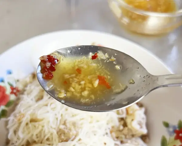 En sked med kryddig sås med vitlök och chili, redo att förhöja smaken på kambodjansk mat.