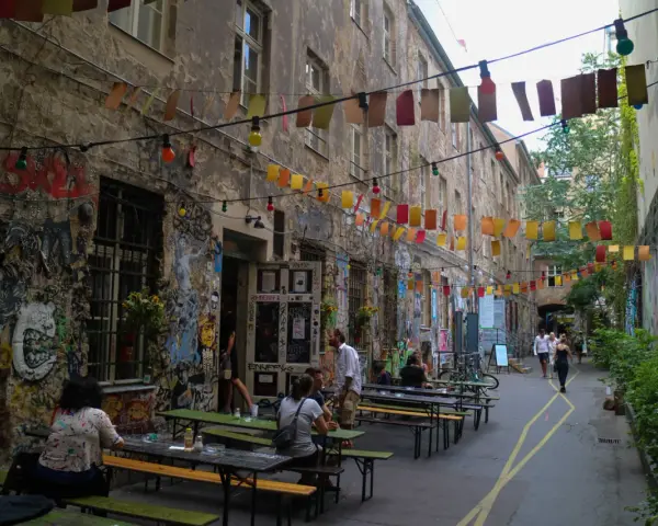 En livlig innergård i Prenzlauer Berg, Berlin, med väggmålningar, ljusslingor och sittplatser utomhus.