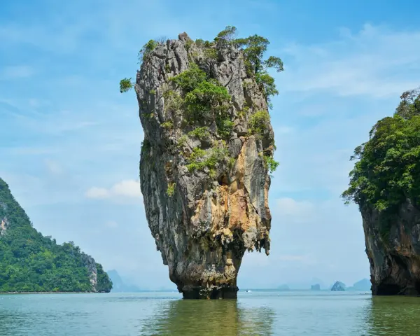 James Bond Island, en ikonisk kalkstensklippa som reser sig ur havet, omgiven av frodiga öar under en klarblå himmel.