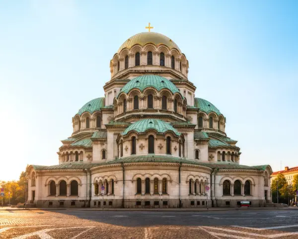 Imponerande kyrka med gröna kupoler och ett gyllene kors i Sofia, Bulgarien. En vacker syn i morgonsolen.