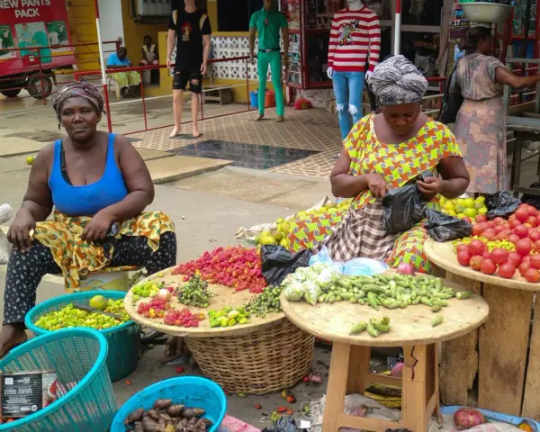 Kvinnor säljer färska grönsaker och frukter på en marknad. En del av deras resa till Ghana.