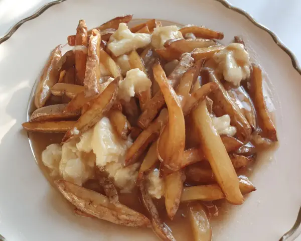 En tallrik med kanadas nationalrätt, poutine: friterade pommes frites, ostbitar och sås.