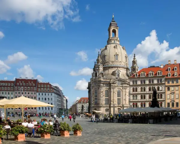 En solig dag i Dresden, Tyskland. Folk sitter vid kafébord på ett torg framför den imponerande Frauenkirche.
