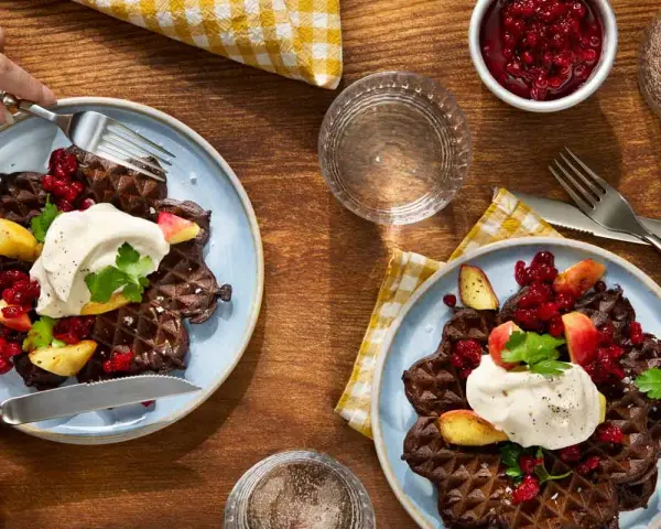 Mörka våfflor med lingon, äpple och grädde – en klassisk svensk frukost.