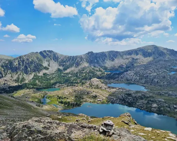 Vacker frankrike natur med berg, sjöar och moln. En stenhög markerar en vandringsled.