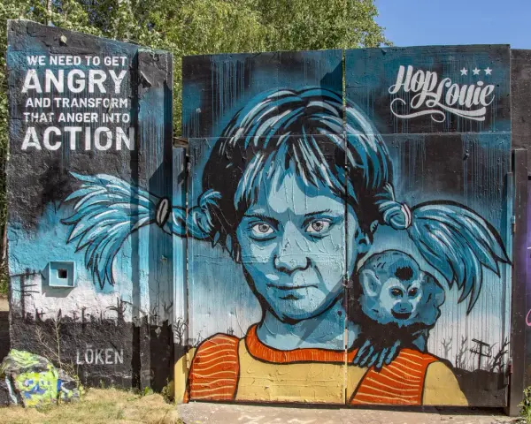 En färgstark graffiti i Stockholm med en flicka och en apa. Texten "WE NEED TO GET ANGRY AND TRANSFORM THAT ANGER INTO ACTION" syns tydligt.