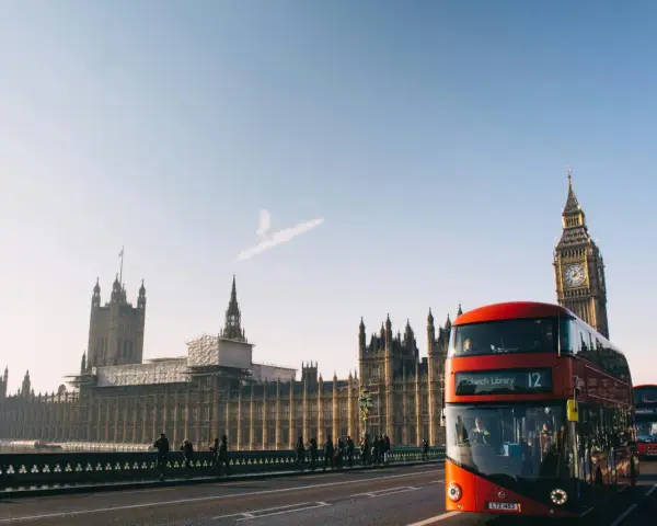 En röd dubbeldäckare passerar Big Ben och Houses of Parliament. En perfekt dag för en **turista i London**.