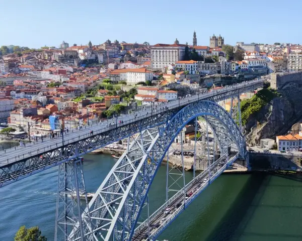 Imponerande bro över Dourofloden i norra Portugal, med en stad full av färgglada hus och kyrkor i bakgrunden.