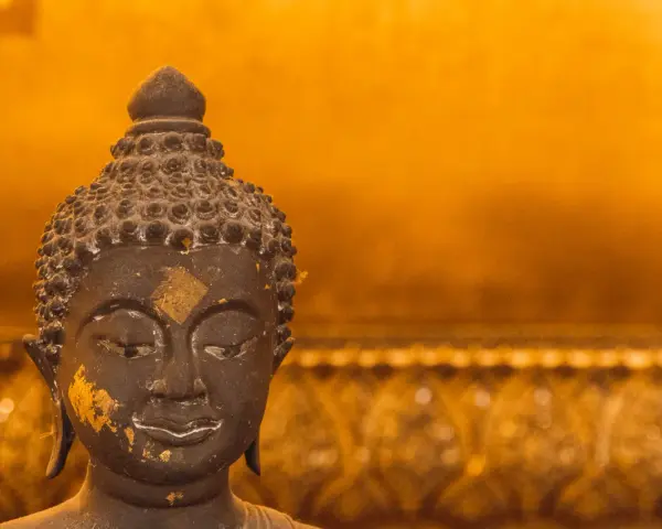 Buddhas ansikte med guldfolierester, en påminnelse om lugn under regnperioden i Asien.