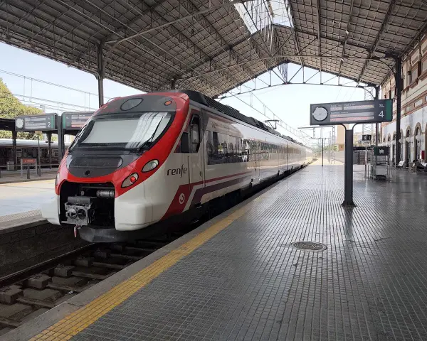 Ett modernt rött och vitt Renfe-tåg står redo på perrongen. Kanske är det dags för ett tåg till Spanien?