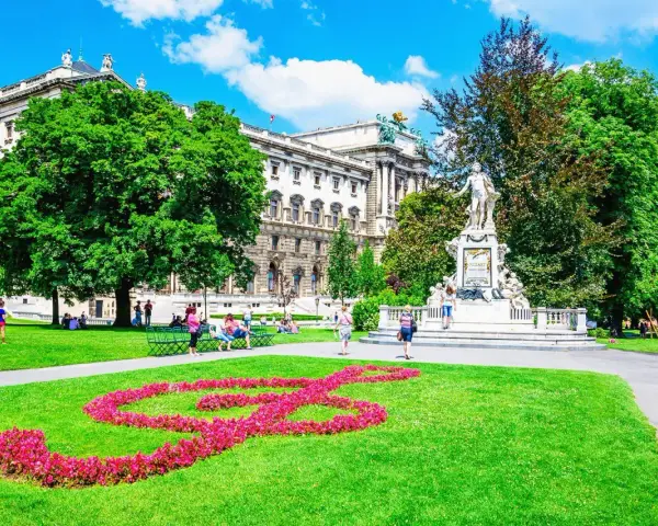 En vacker sommardag i Wien. En blomsterformation i form av en fiolnyckel lyser upp gräsmattan framför Mozarts staty. Ett perfekt ställe att se i Wien.