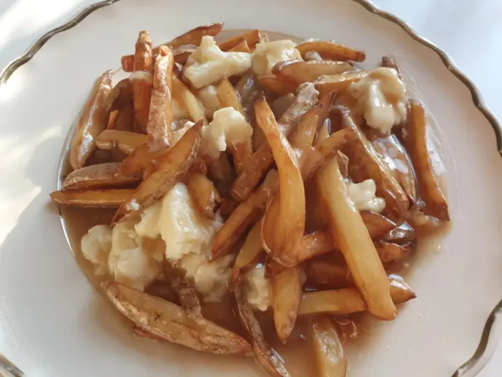 En tallrik med kanadas nationalrätt, poutine: friterade pommes frites, ostbitar och sås.