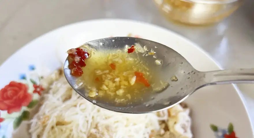 En sked med kryddig sås med vitlök och chili, redo att förhöja smaken på kambodjansk mat.
