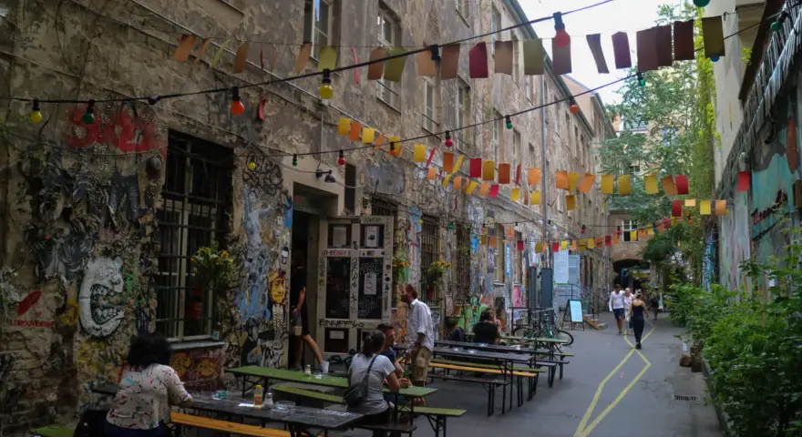 En livlig innergård i Prenzlauer Berg, Berlin, med väggmålningar, ljusslingor och sittplatser utomhus.