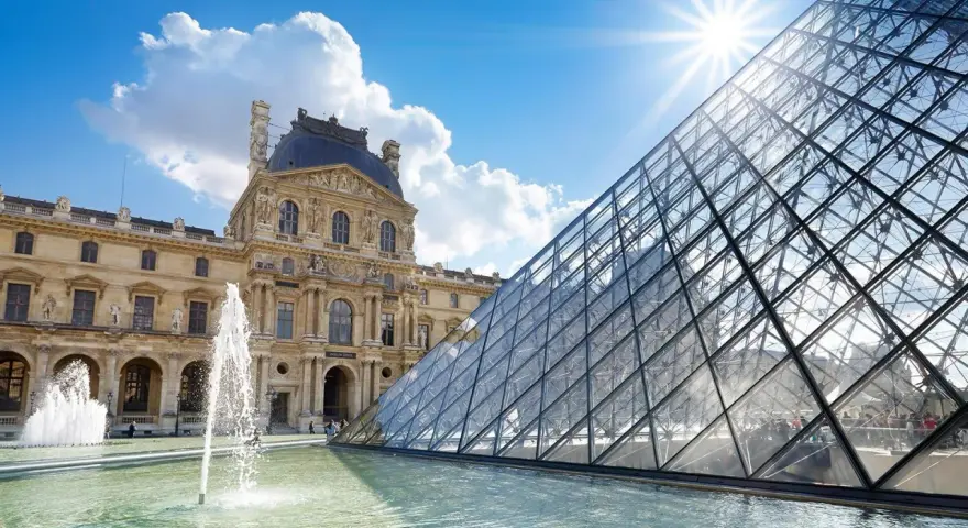 Louvren, ett berömt konstmuseum i Paris, med sin ikoniska glaspyramid och fontäner i förgrunden under en solig himmel.