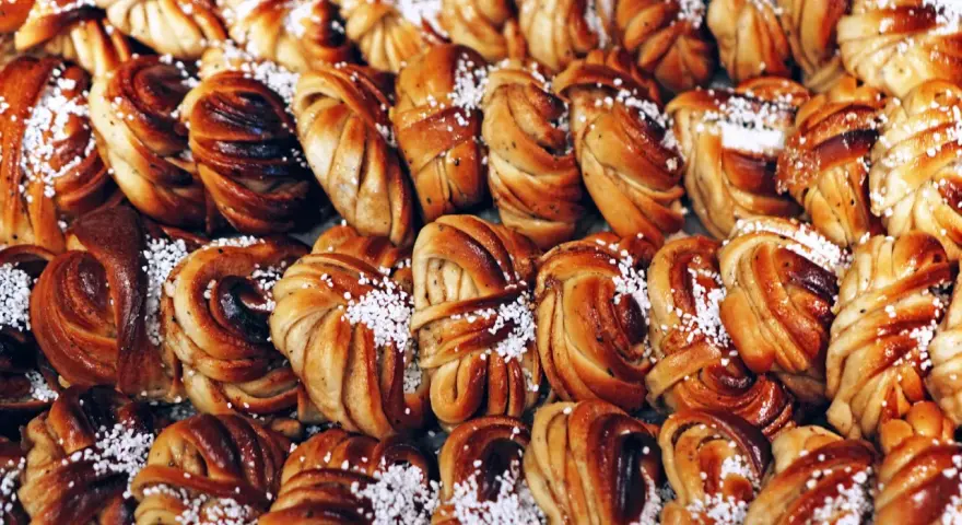 En stor bricka med gyllenbruna kanelbullar, en svensk specialitet, toppade med pärlsocker.