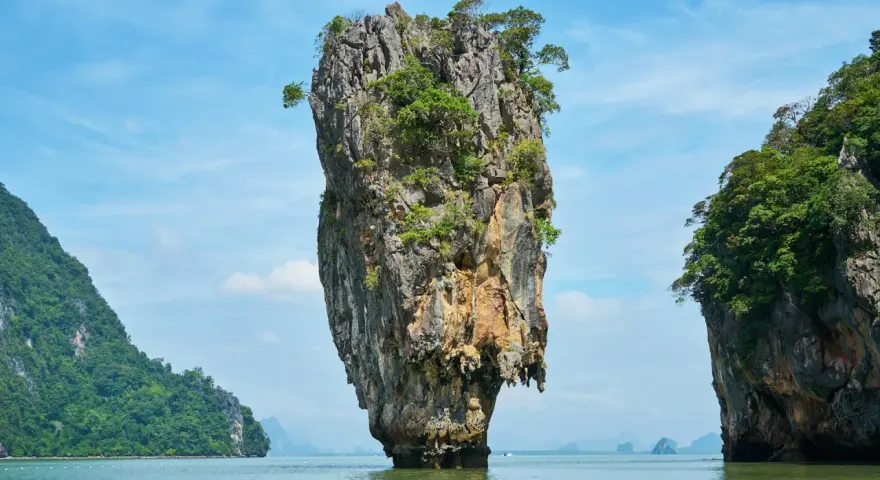 James Bond Island, en ikonisk kalkstensklippa som reser sig ur havet, omgiven av frodiga öar under en klarblå himmel.