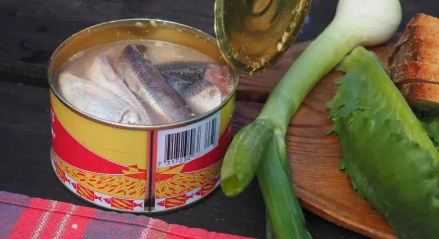 En burk med sill, en klassisk del av **comida tipica sueca**, ligger bredvid färska grönsaker och bröd.