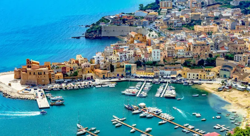 En charmig hamn i Palermo, Sicilien, med färgglada hus och många båtar i det turkosa vattnet.