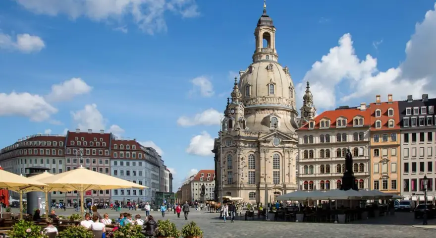 En solig dag i Dresden, Tyskland. Folk sitter vid kafébord på ett torg framför den imponerande Frauenkirche.