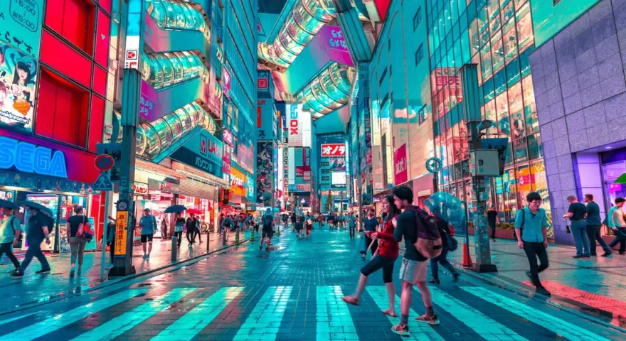 Neonbelyst gata i Tokyo, perfekt för din tokyo reseguide. Människor promenerar under paraplyer i regnet bland blinkande skyltar.