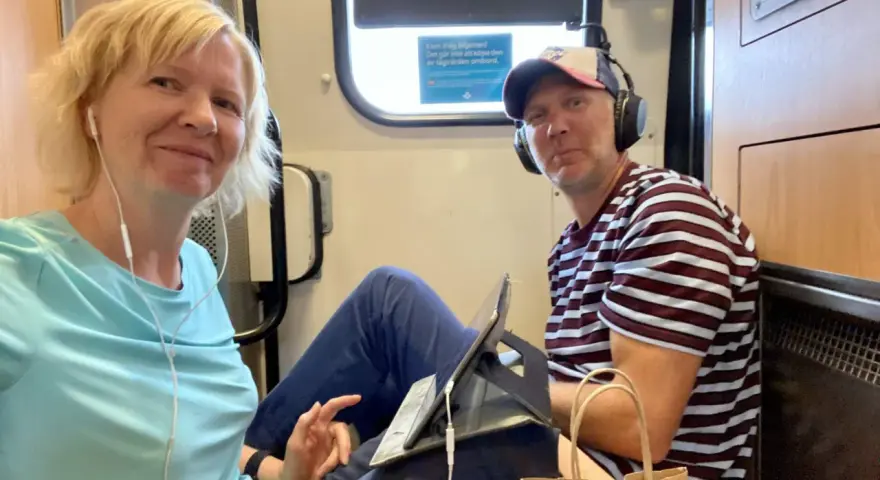 Ett par på tåget, redo för en resa. Kanske är det ett tåg till Grekland, med hörlurar och surfplatta för underhållning.