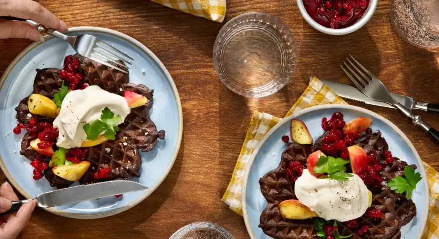 Mörka våfflor med lingon, äpple och grädde – en klassisk svensk frukost.