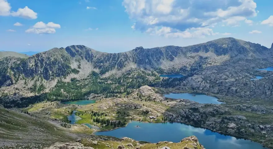 Vacker frankrike natur med berg, sjöar och moln. En stenhög markerar en vandringsled.