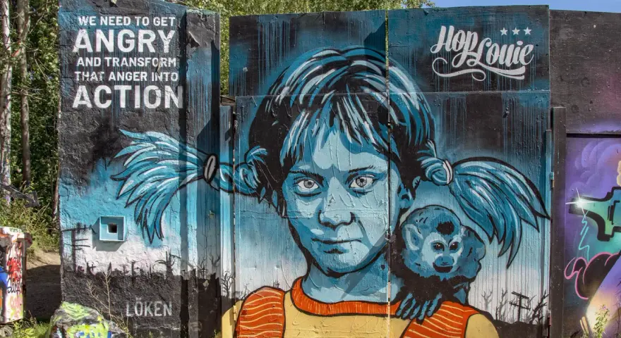 En färgstark graffiti i Stockholm med en flicka och en apa. Texten "WE NEED TO GET ANGRY AND TRANSFORM THAT ANGER INTO ACTION" syns tydligt.