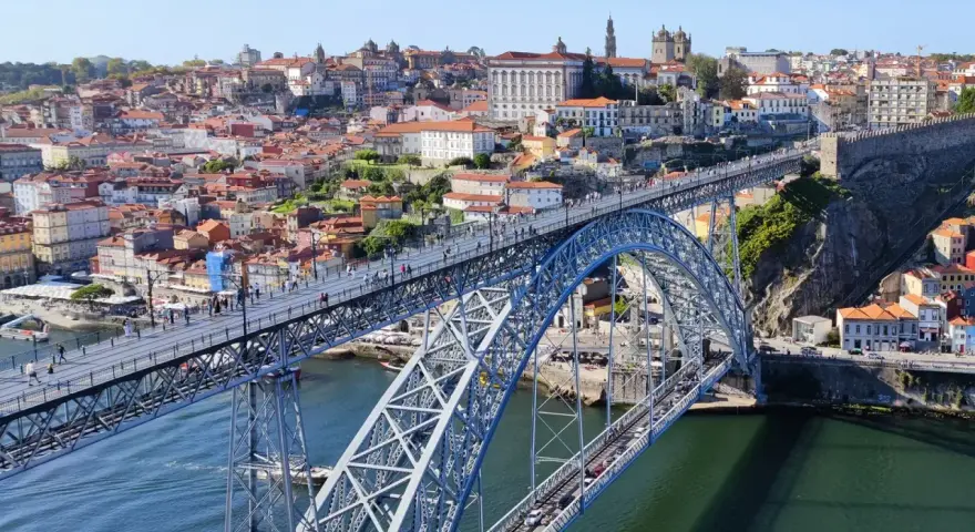 Imponerande bro över Dourofloden i norra Portugal, med en stad full av färgglada hus och kyrkor i bakgrunden.