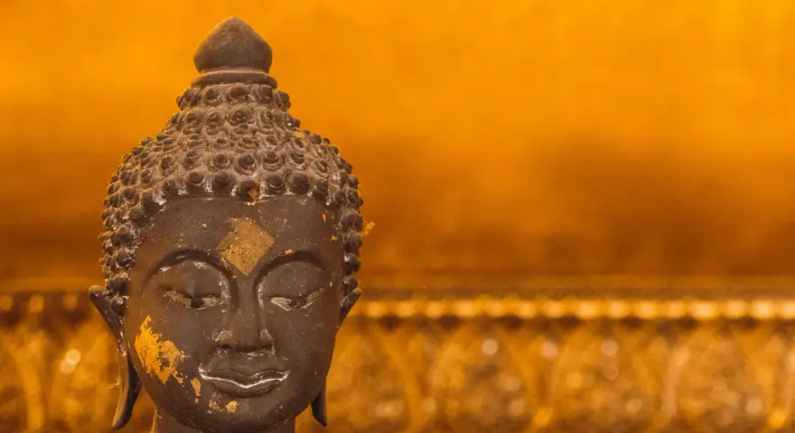 Buddhas ansikte med guldfolierester, en påminnelse om lugn under regnperioden i Asien.