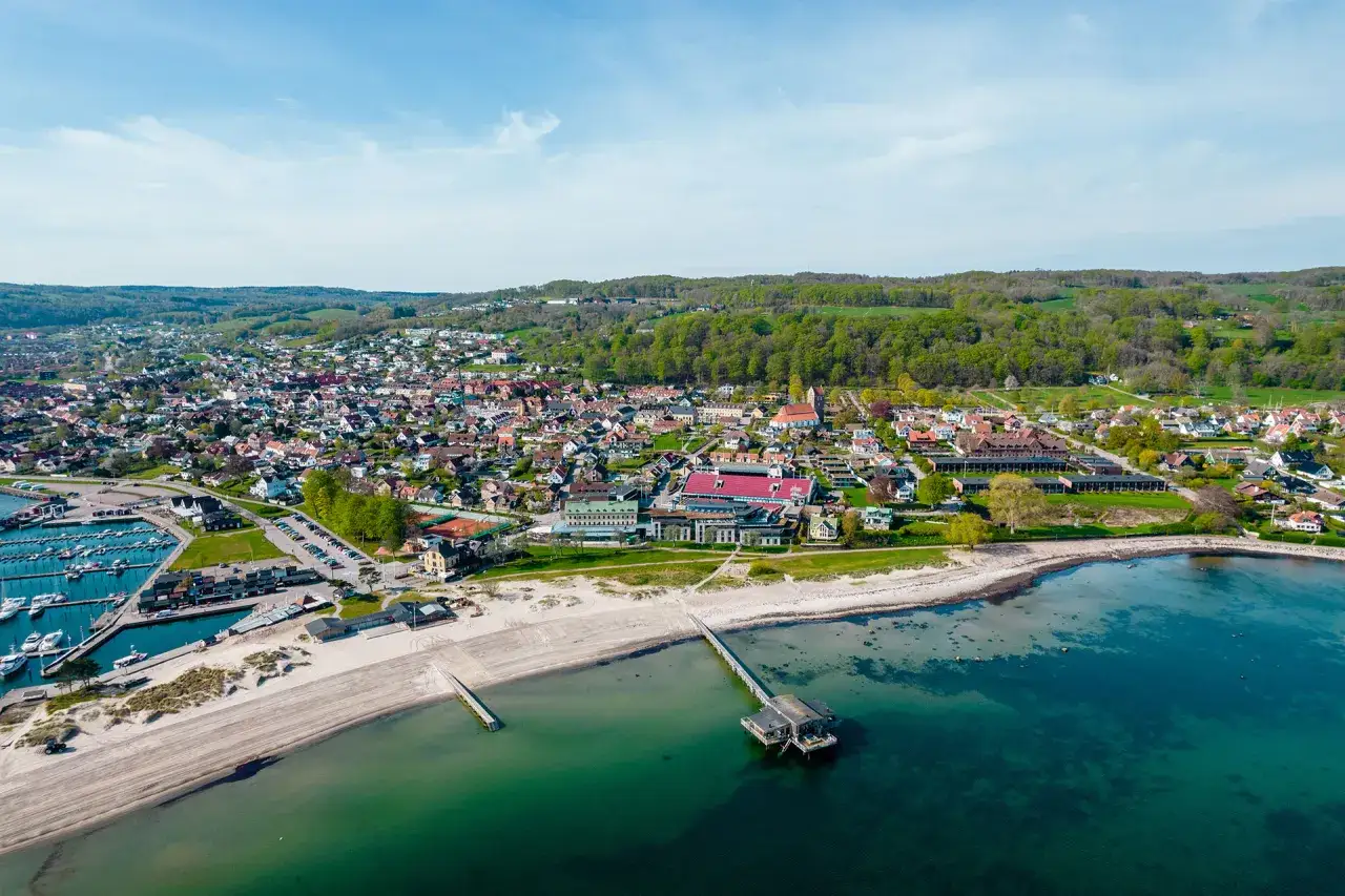 Luftfoto &ouml;ver B&aring;stad med hamn, strand och bebyggelse. En vacker dag som p&aring;minner om Stockholmsveckan i B&aring;stad.