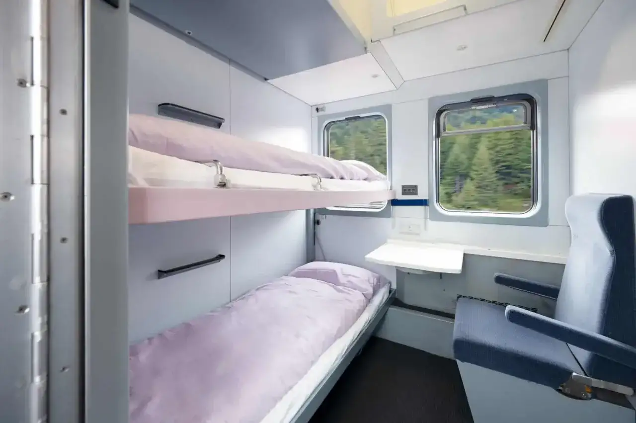 Sovplats i ett natt&aring;g till Berlin. Tv&aring; v&aring;ningss&auml;ngar med lila s&auml;ngkl&auml;der och ett f&ouml;nster med utsikt &ouml;ver skogen.