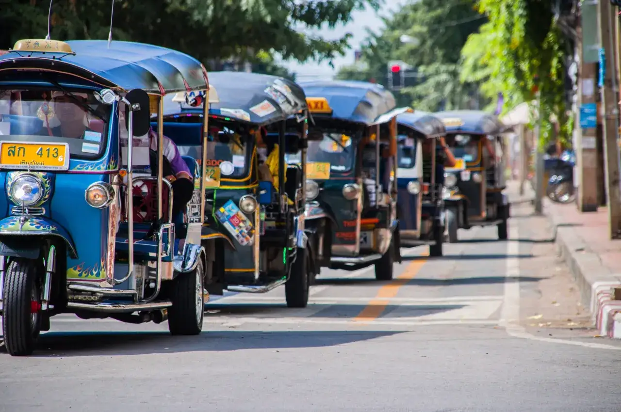Rad av f&auml;rgglada tuk tuk-taxibilar i Thailand, redo att ta passagerare p&aring; en tur.