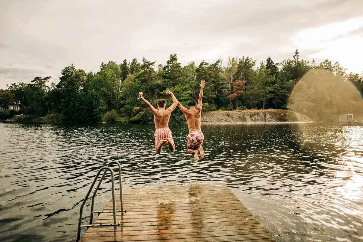 Tv&aring; killar hoppar fr&aring;n en brygga vid en badplats i Stockholm.