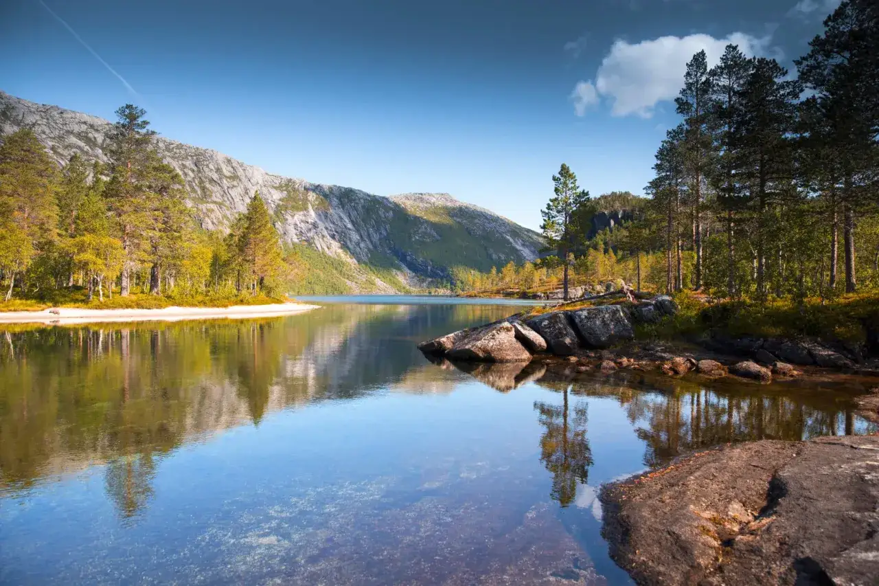 En spegelblank sj&ouml; reflekterar h&ouml;stf&auml;rgad skog och berg. En bit av den vackra europa natur.