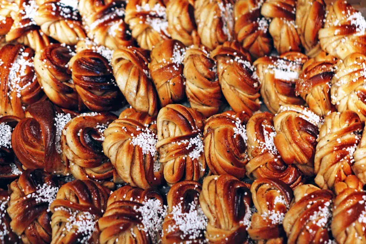 En närbild på kanelbullar, en klassisk svensk fika. Dessa gyllene bakverk är strösslade med pärlsocker.