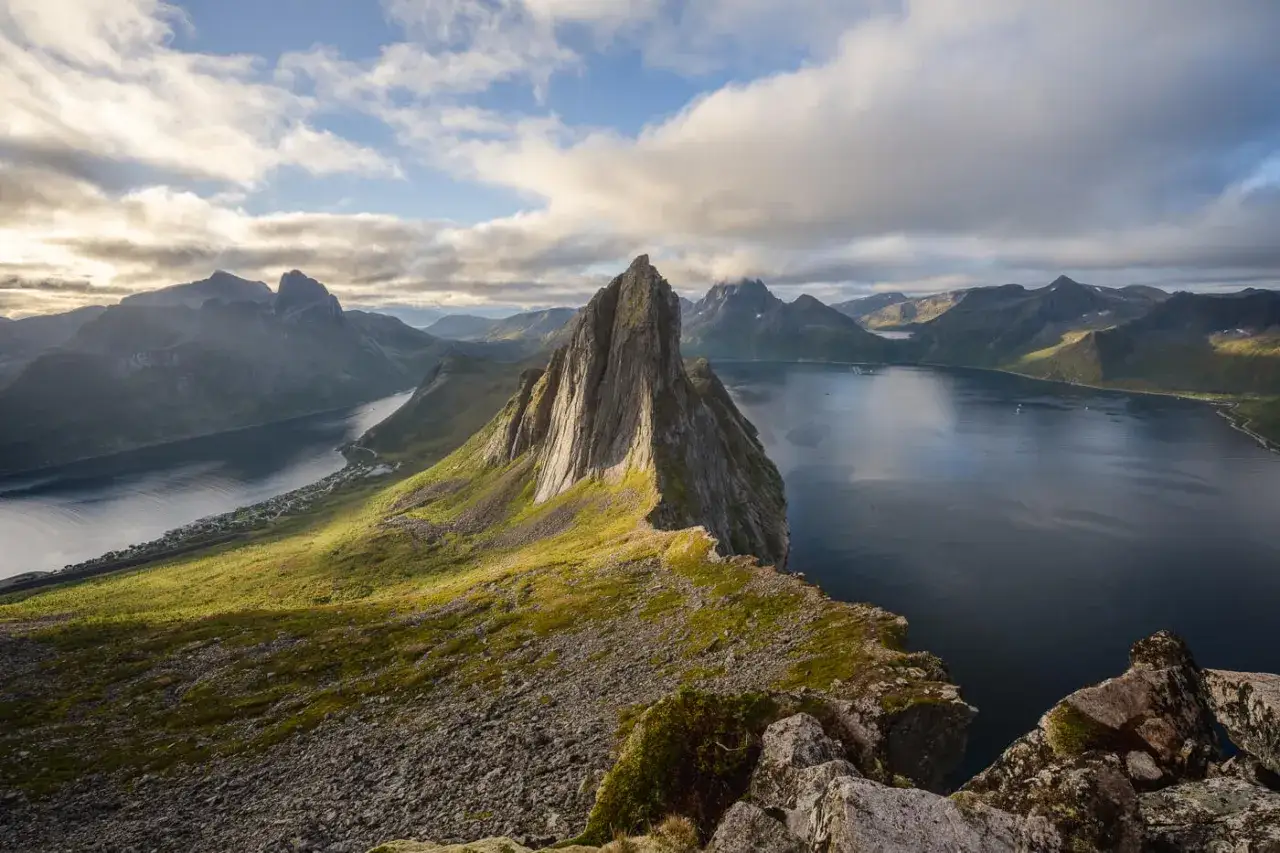 Majest&auml;tisk bergstopp reser sig ur havet, en dr&ouml;m f&ouml;r alla som vill vandra i Norge. Gr&ouml;nskande sluttningar m&ouml;ter m&ouml;rkt vatten under en dramatisk himmel.