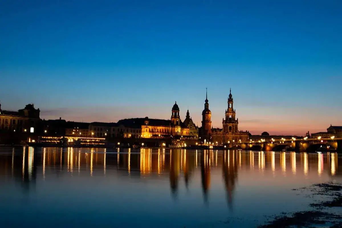 Dresden Tyskland vid skymning. En vacker stadssilhuett med upplysta byggnader och deras reflektioner i floden Elbe.