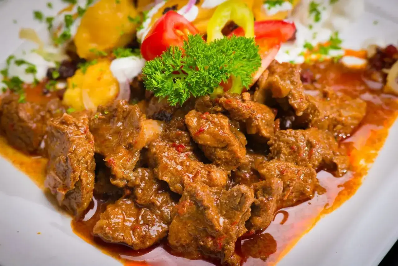 En mustig k&ouml;ttgryta, en klassisk ungersk r&auml;tt, serveras med potatis, gr&auml;ddfil och gr&ouml;nsaker. En smak av mat i Budapest.