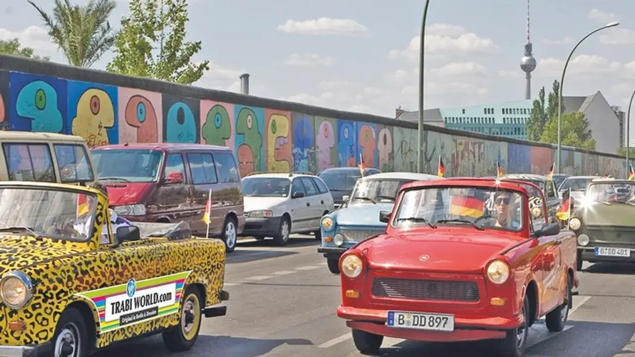 Trabantbilar i parad l&auml;ngs Berlinmuren, en f&auml;rgstark sev&auml;rdhet f&ouml;r din berlin reseguide.