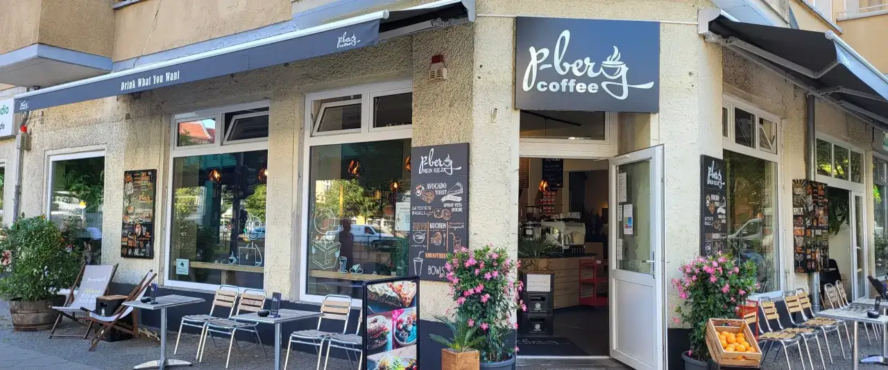 Ett mysigt caf&eacute; i Prenzlauer Berg med uteservering och en skylt som s&auml;ger 