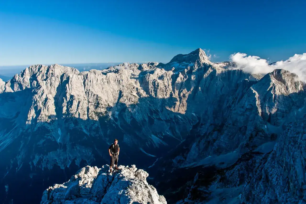 Vandrare p&aring; en klippavsats med majest&auml;tiska berg i Slovenien. Denna otroliga slovenien natur bjuder p&aring; hisnande vyer.
